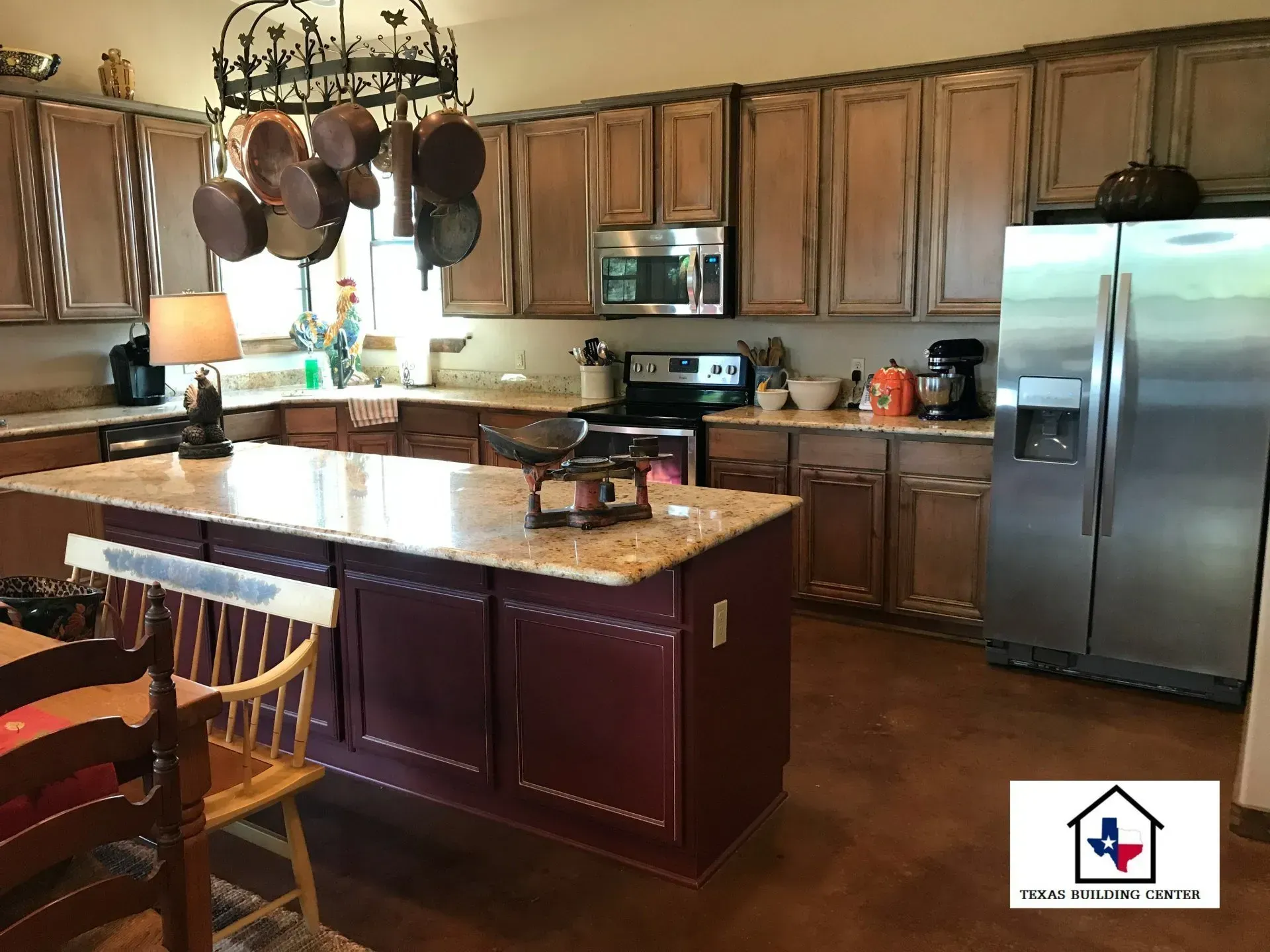 Kitchen with a granite island, stainless steel fridge, and brown cabinets.