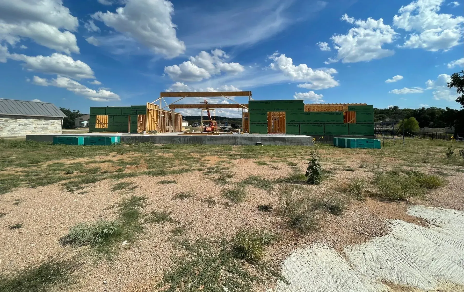Construction site with wooden frame of house against a blue sky.