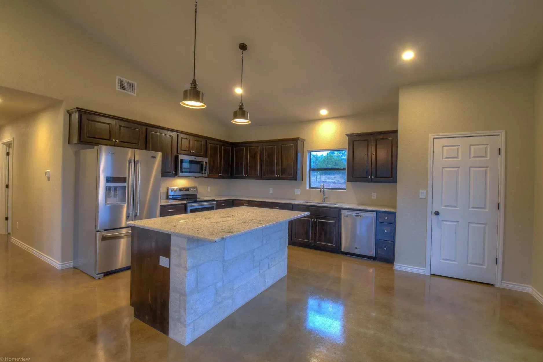 Modern kitchen with dark wood cabinets, stainless steel appliances, and a stone island.
