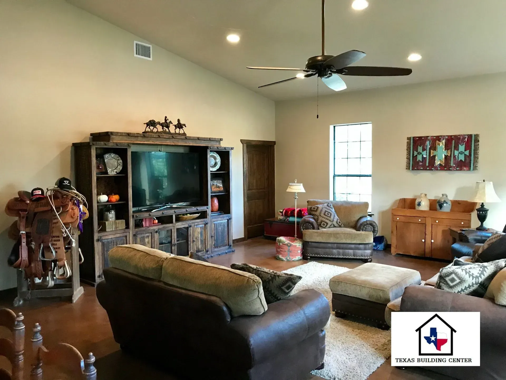 Living room with rustic furniture, TV, and a saddle.
