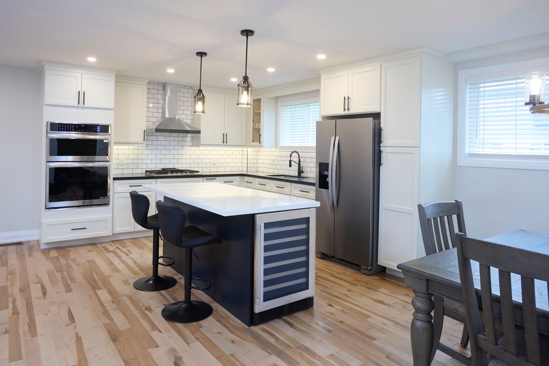 Modern kitchen with white cabinets, stainless steel appliances, and dark blue island with seating.