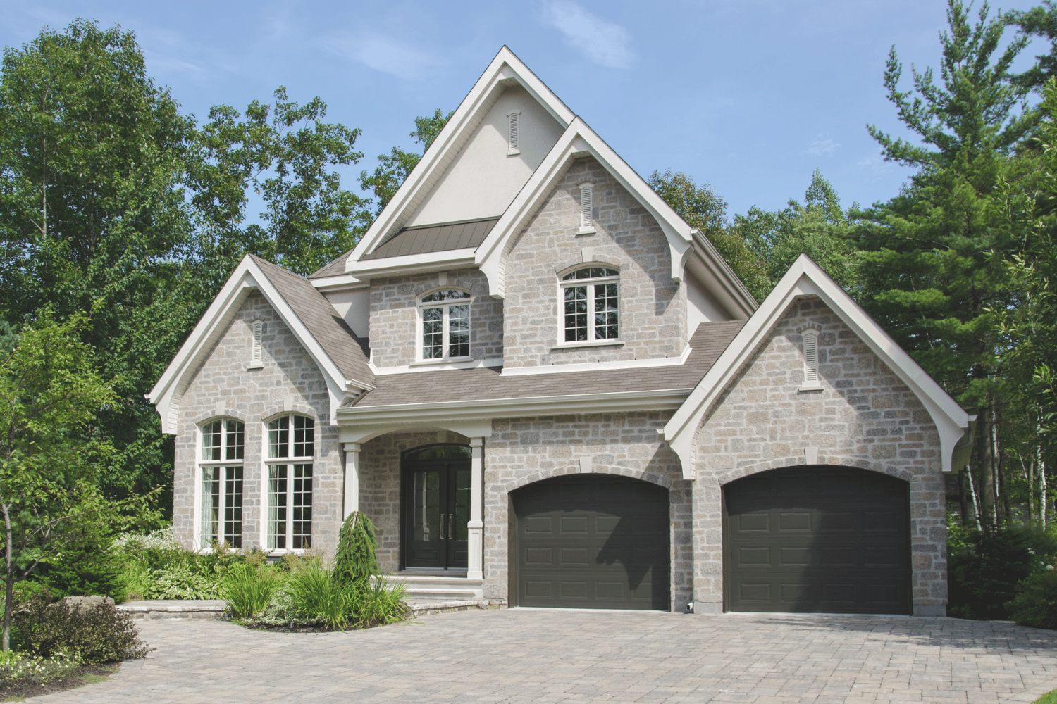 A modern white house with a black garage door and a car parked in front of it.
