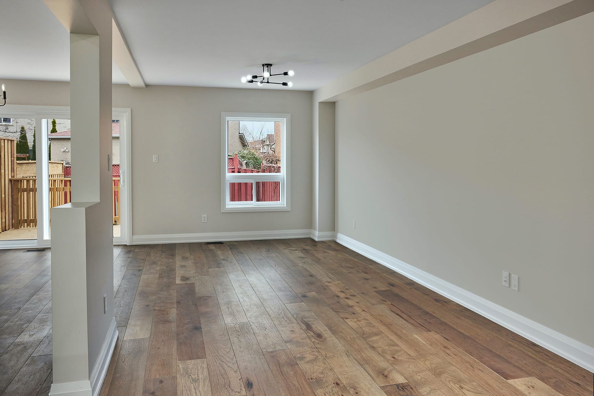 Empty room with hardwood floors, a window, and neutral-colored walls.
