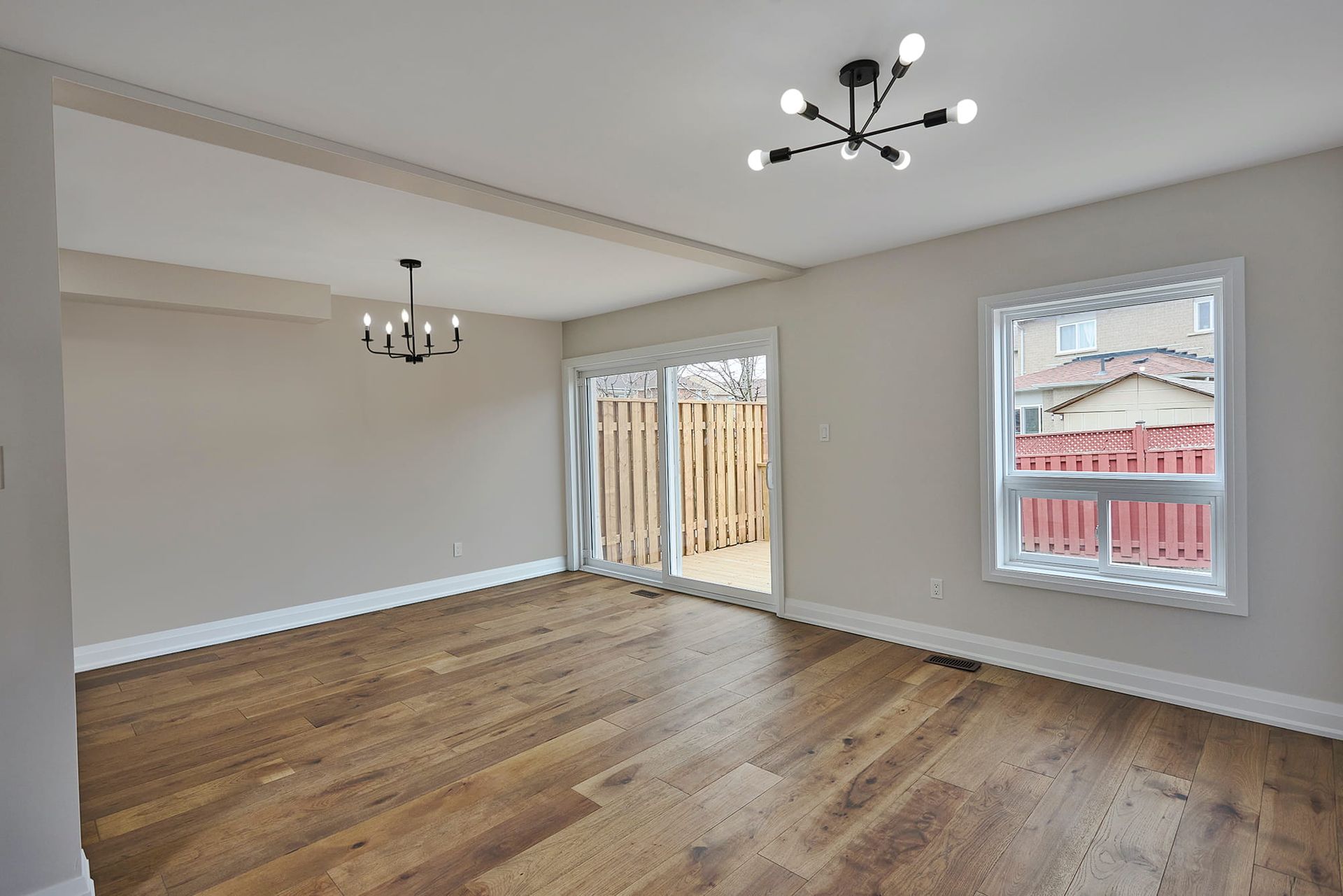 Empty dining room with hardwood floors, sliding glass door, and two light fixtures.