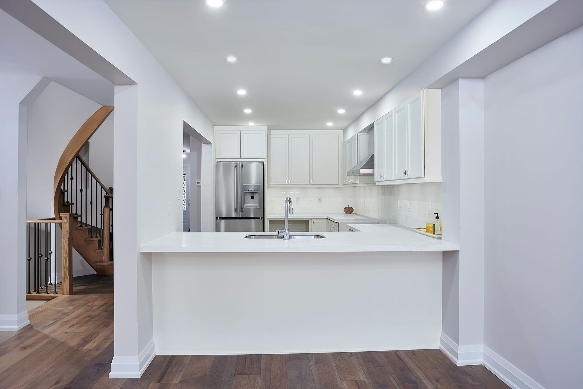 Modern kitchen with white cabinets, countertop, and stainless steel appliances.