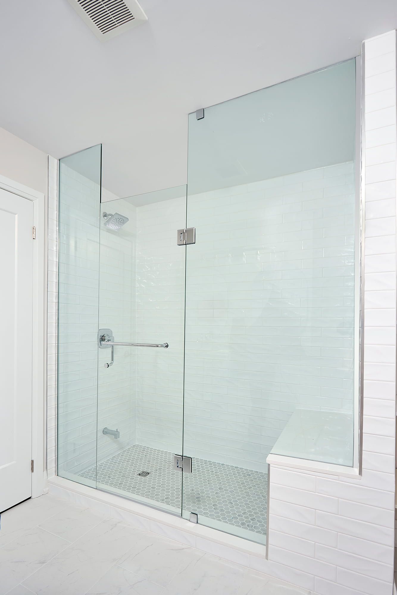Glass shower enclosure in a white bathroom.