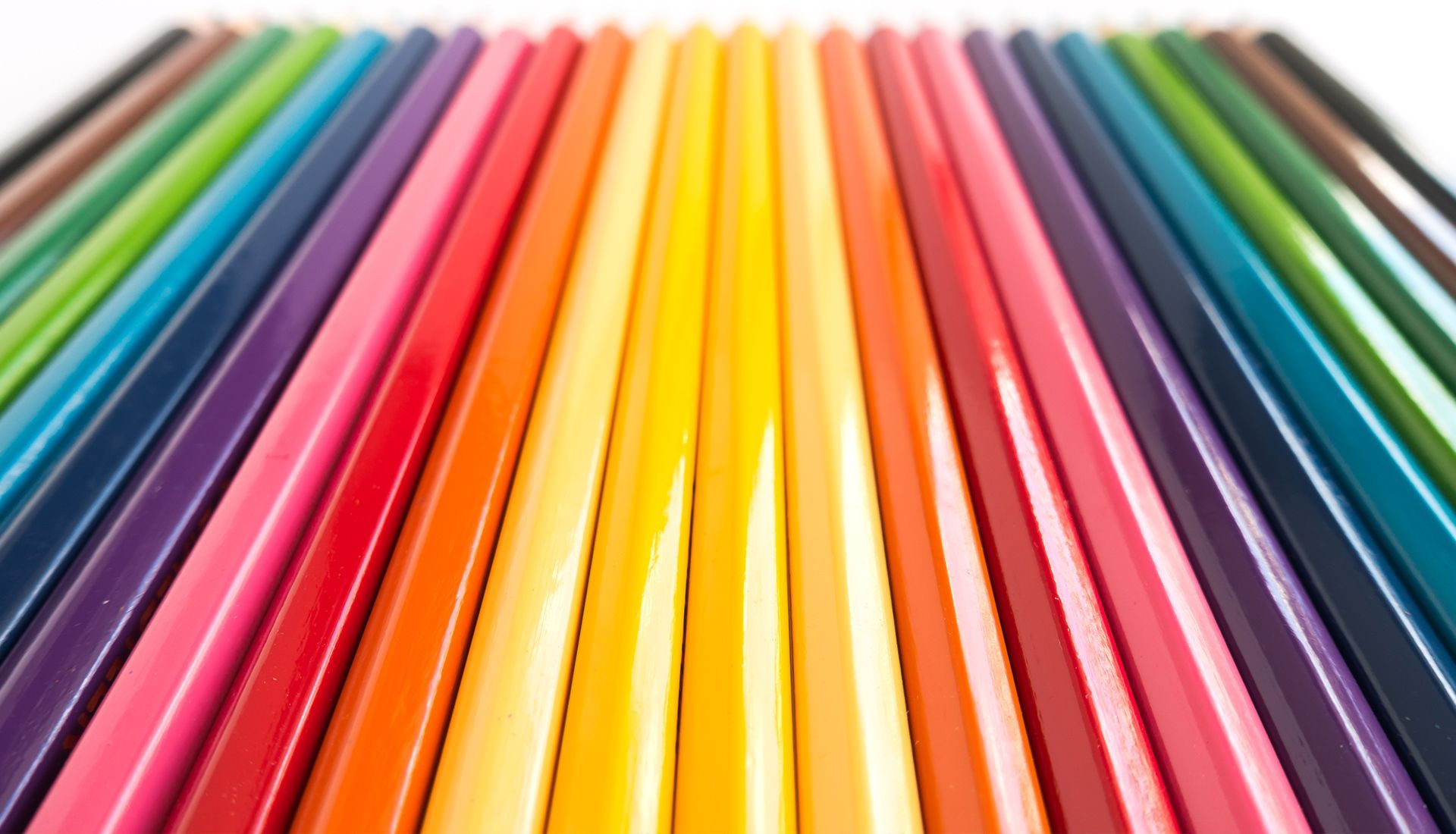 Row of colorful pencils, arranged in a spectrum, angled towards the viewer.
