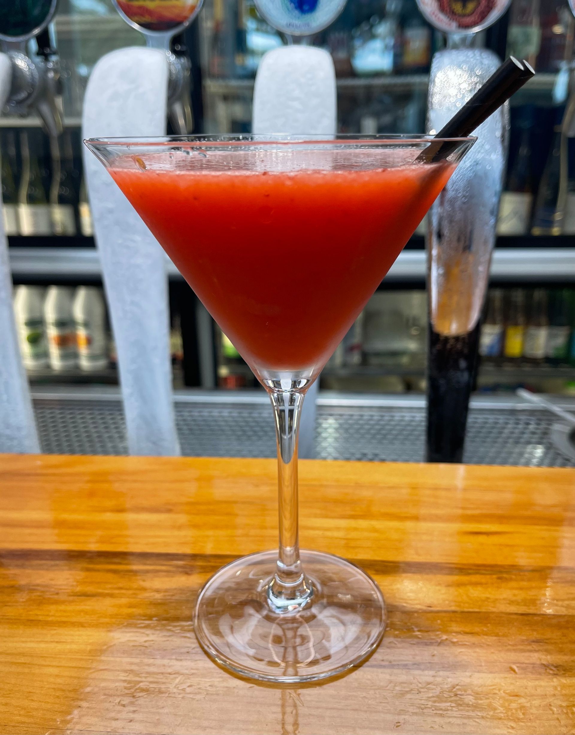 A creamy, blended piña colada in a tulip glass with pineapple wedge garnish and a striped straw.