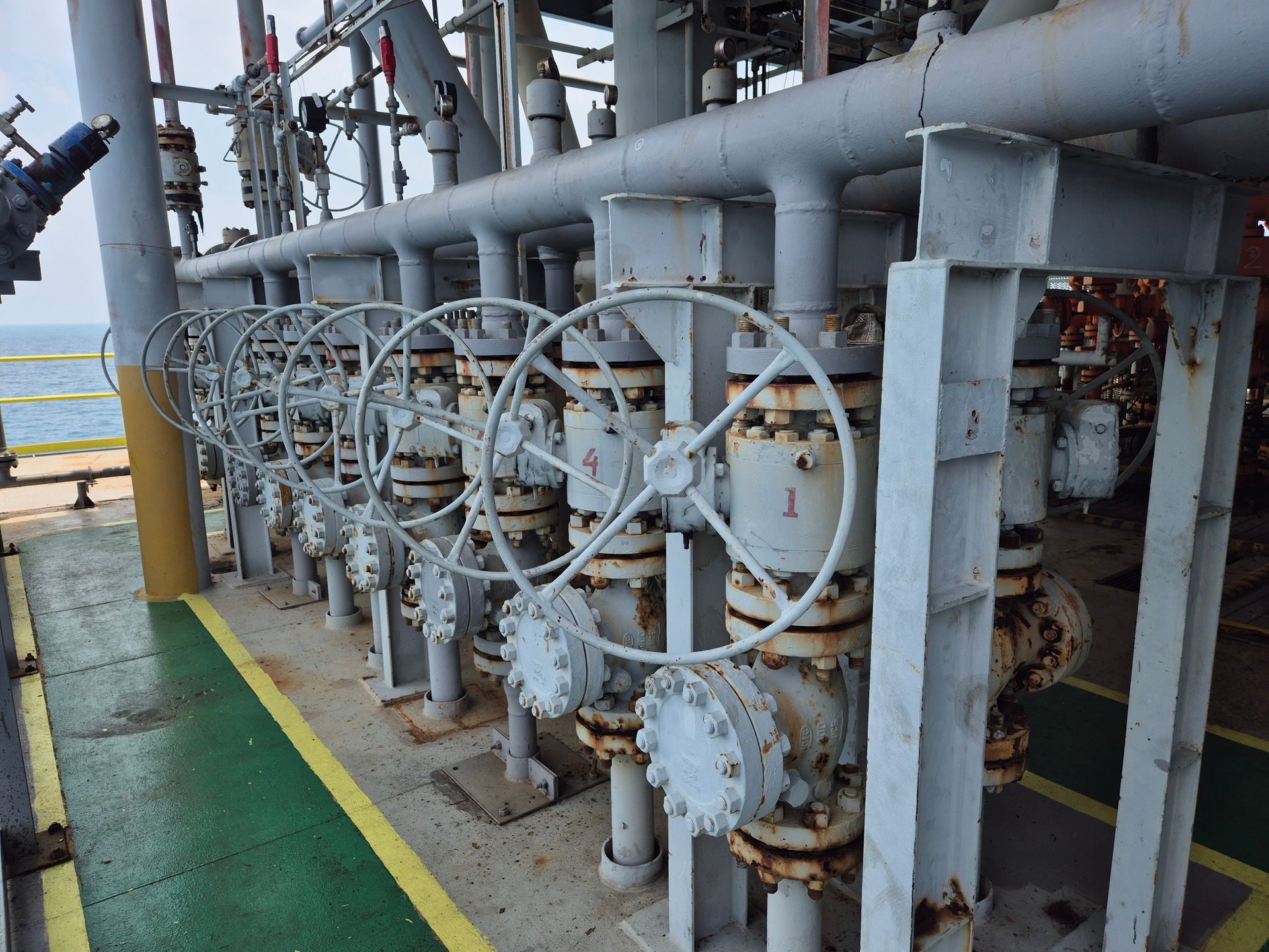 Row of gray industrial valves with large handwheels, mounted on pipes.