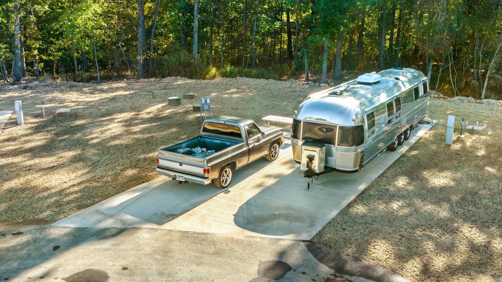 A silver airstream trailer is driving down a dirt road.