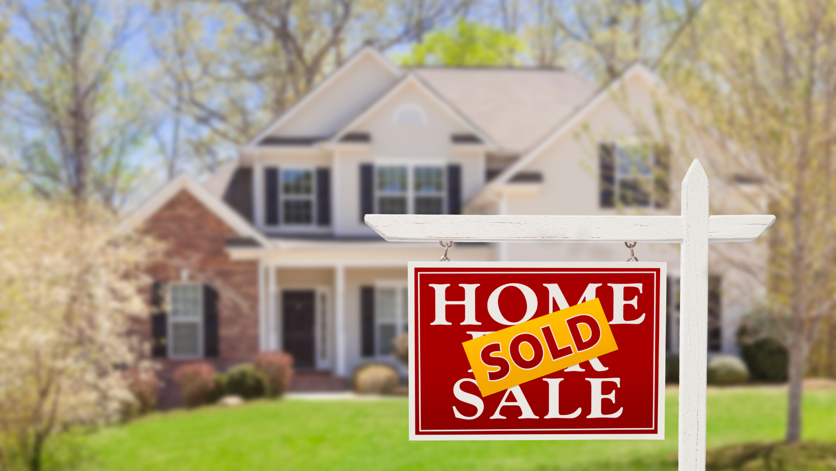 Picture of a two story home with a for sale sign that has sold on it.