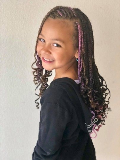 Girl with braided hair and pink highlights smiling, wearing a black top.