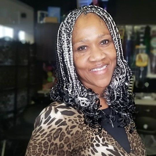Woman with black and silver braids smiles, wearing a leopard print top.