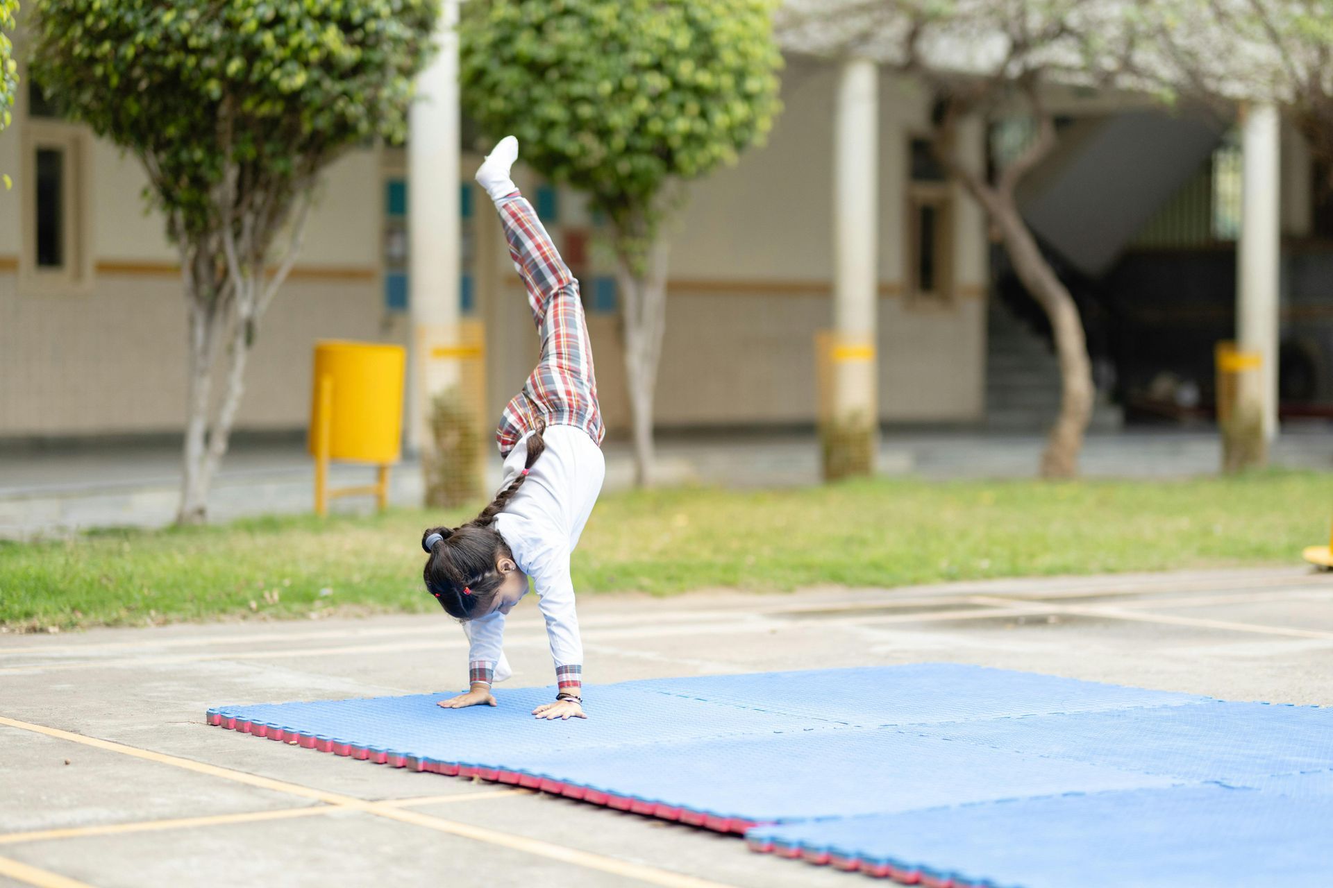 A young boy is doing a handstand on a blue mat.
