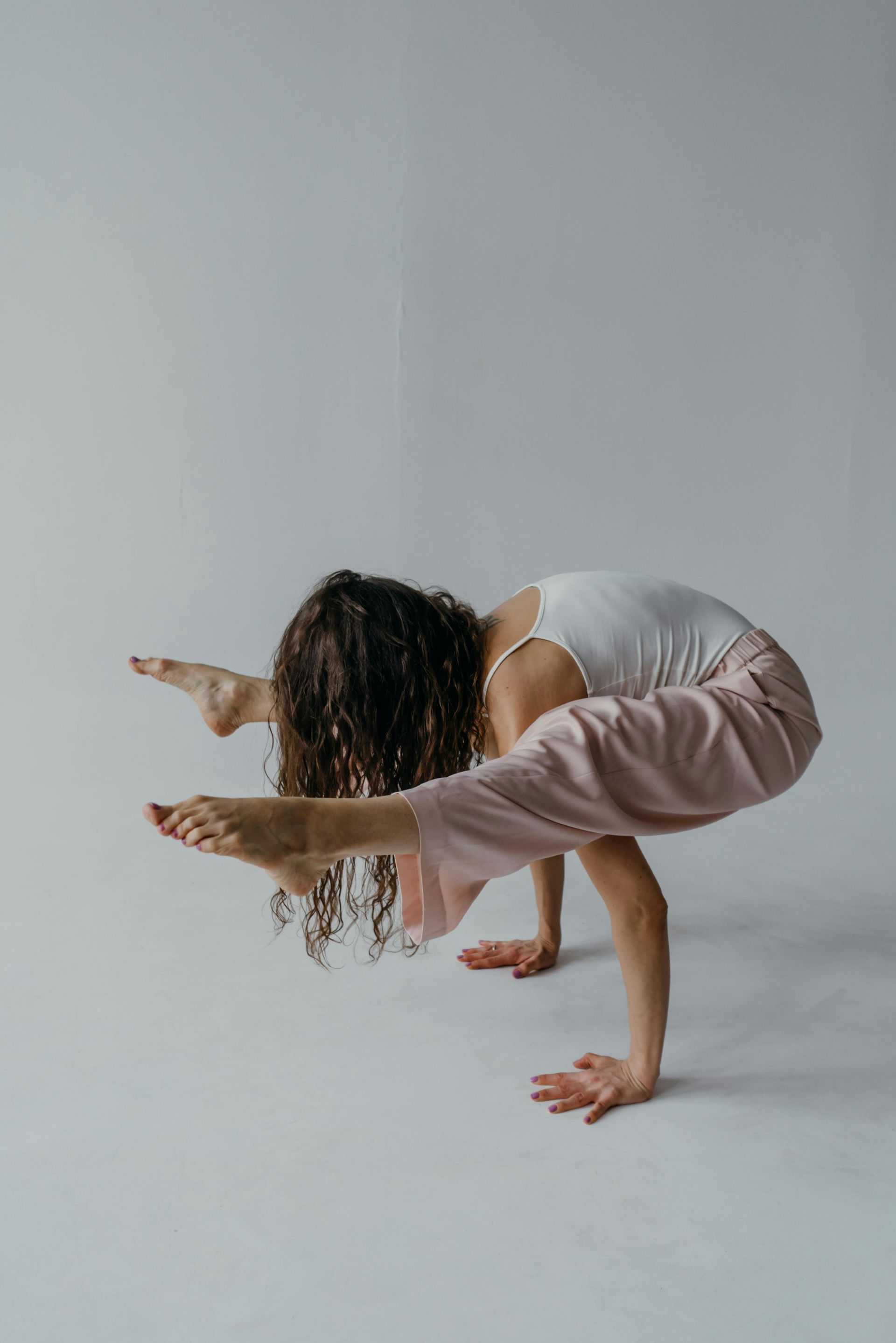 A woman is doing a handstand on a white background.