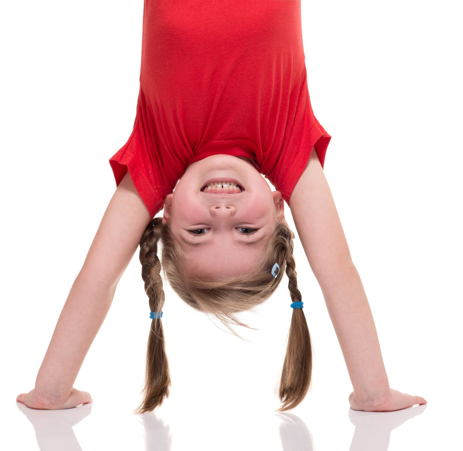 A little girl in a red shirt is upside down