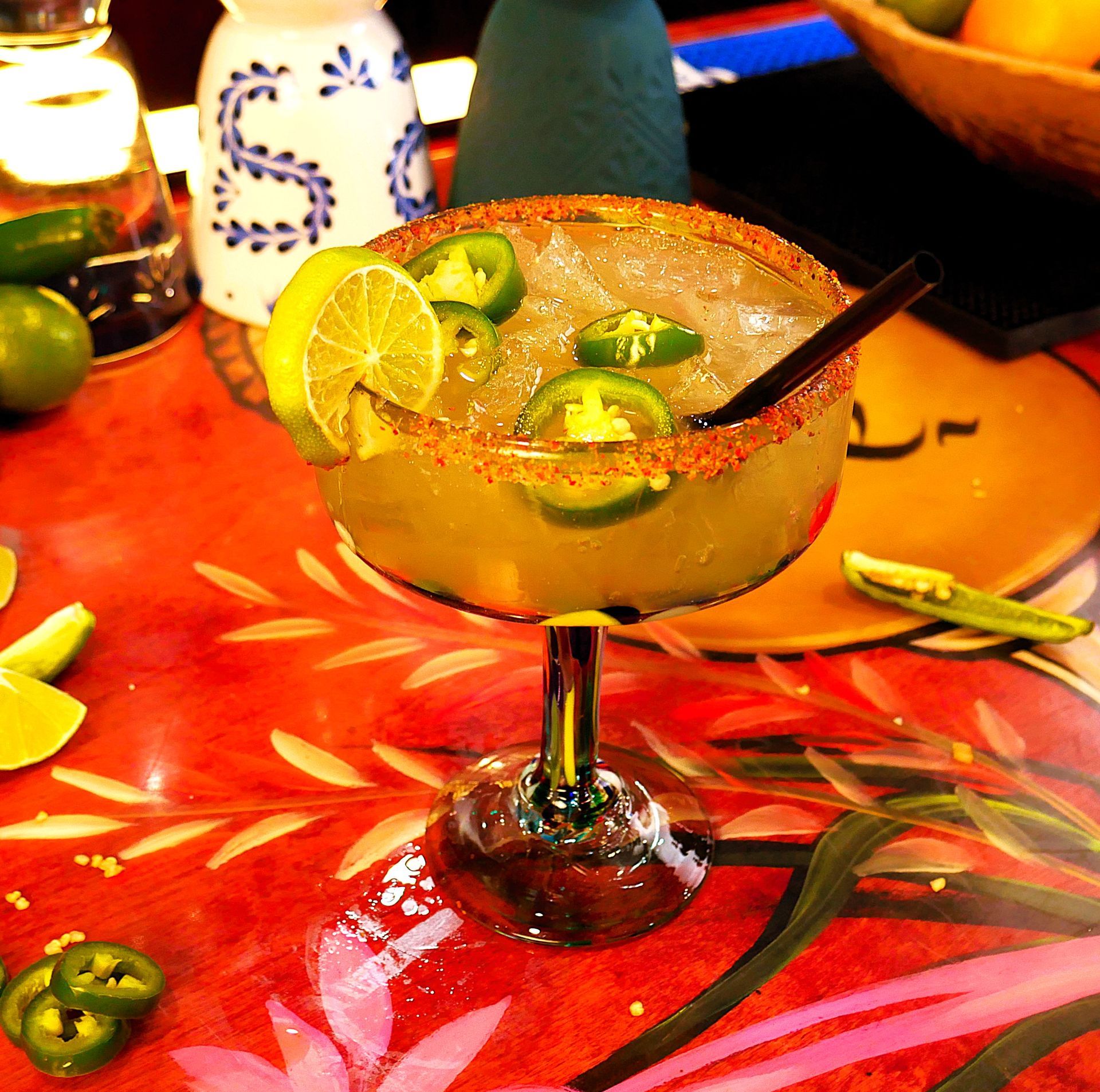 A margarita with jalapenos and lemon slices on a table