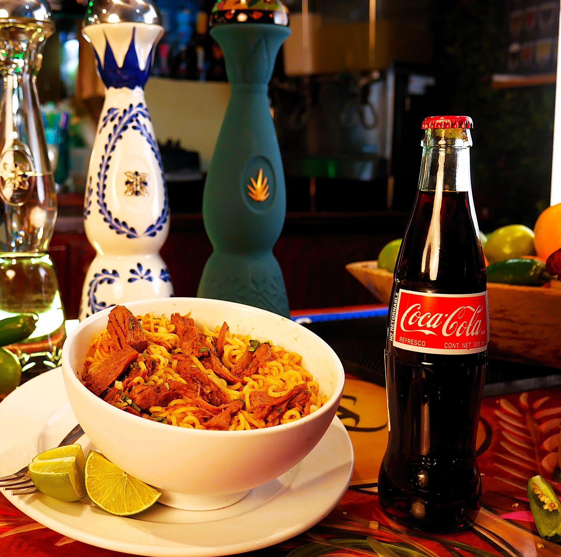 A bottle of coca cola sits next to a bowl of food