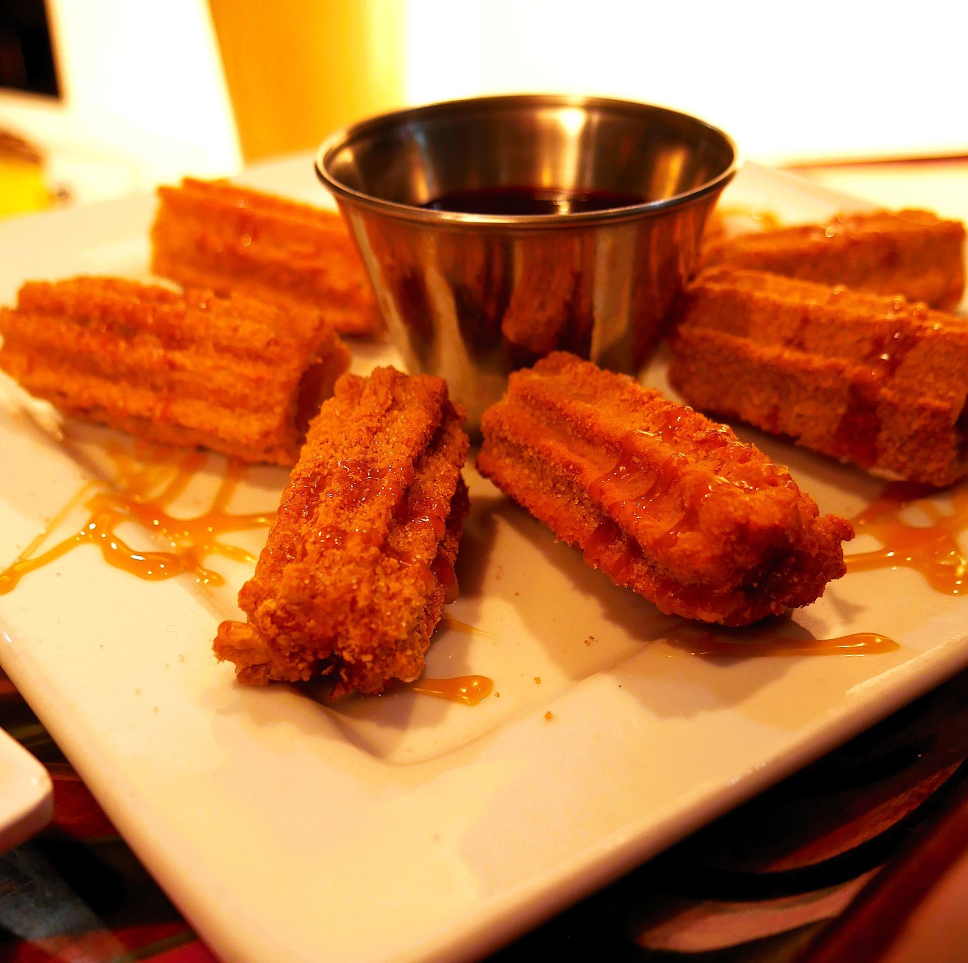 A plate of churros with dipping sauce and a cup of dipping sauce
