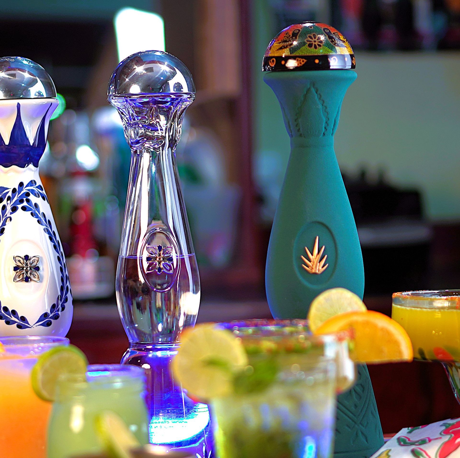 A bottle of tequila sits on a table with other drinks