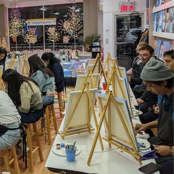 A group of people are sitting at easels in front of an exit sign