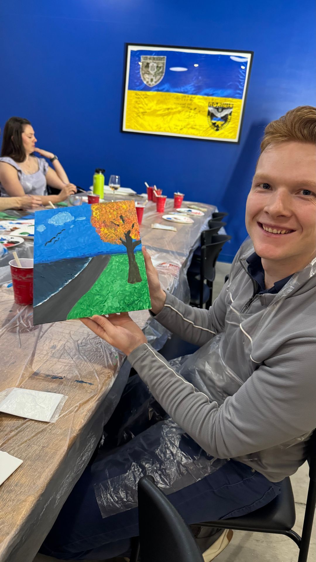 friends posing with their canvases from painting class