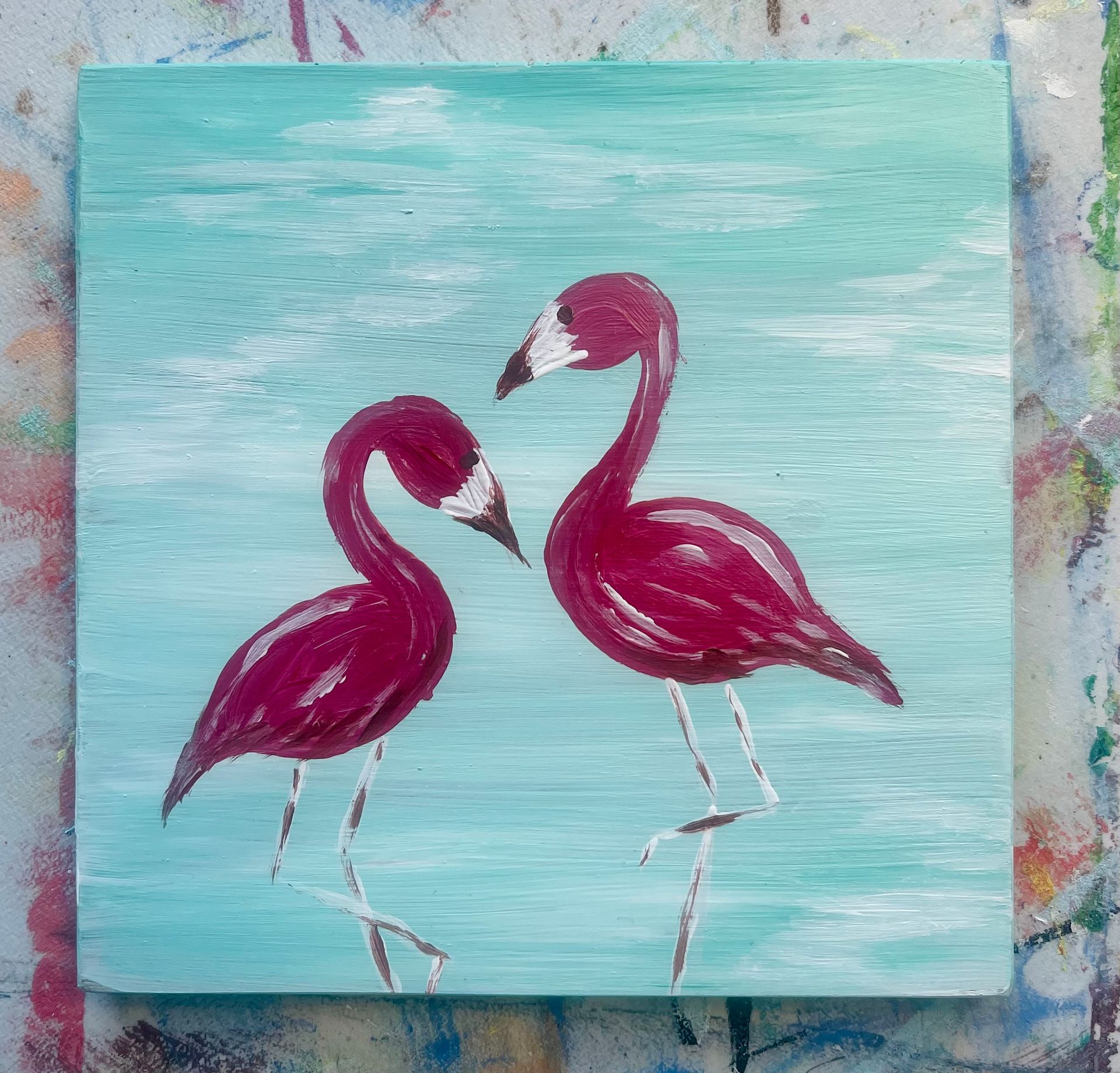 A painting of two flamingos on a blue background