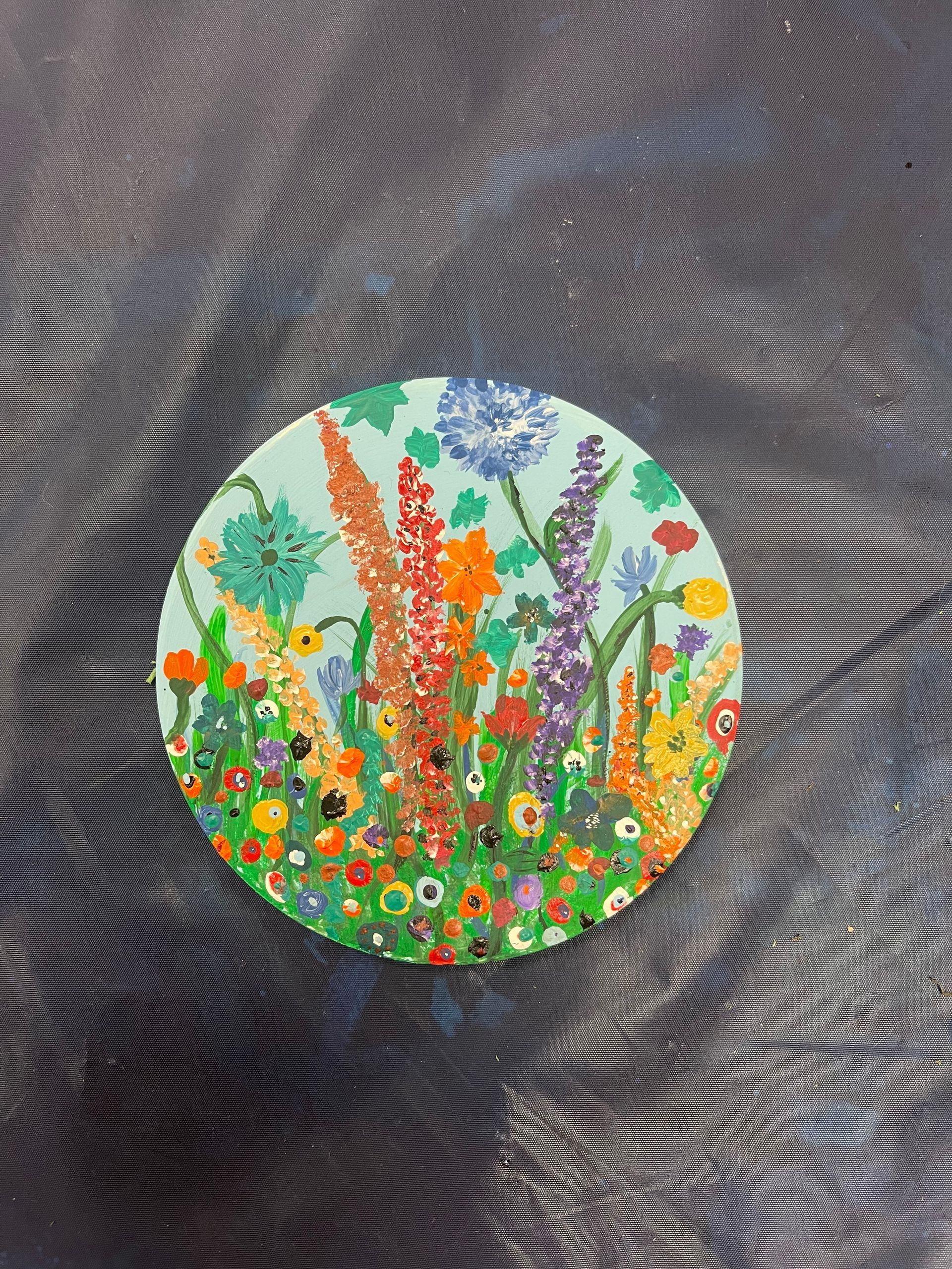 A painting of flowers on a circle on a table.