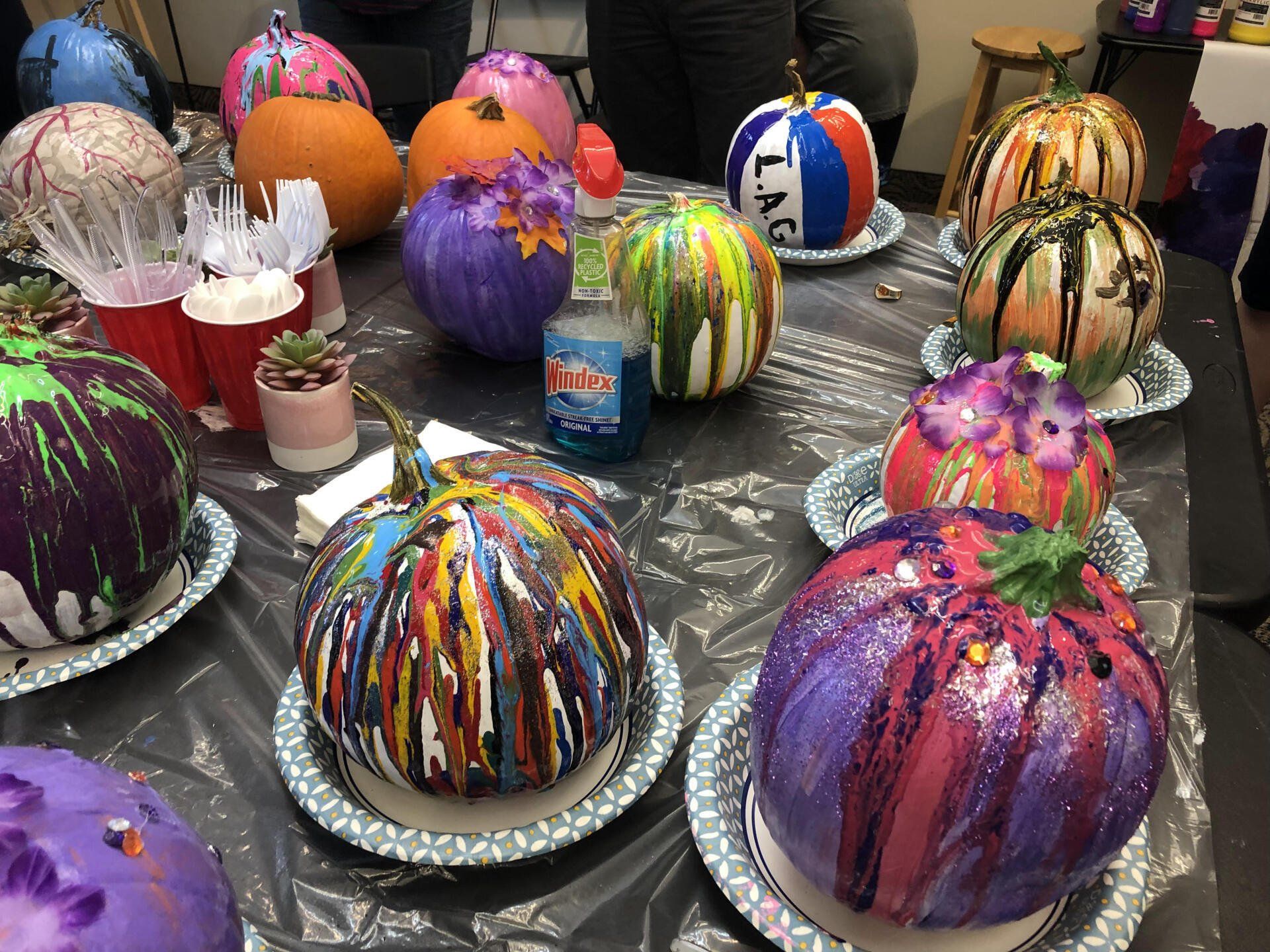 A table topped with plates of painted pumpkins.