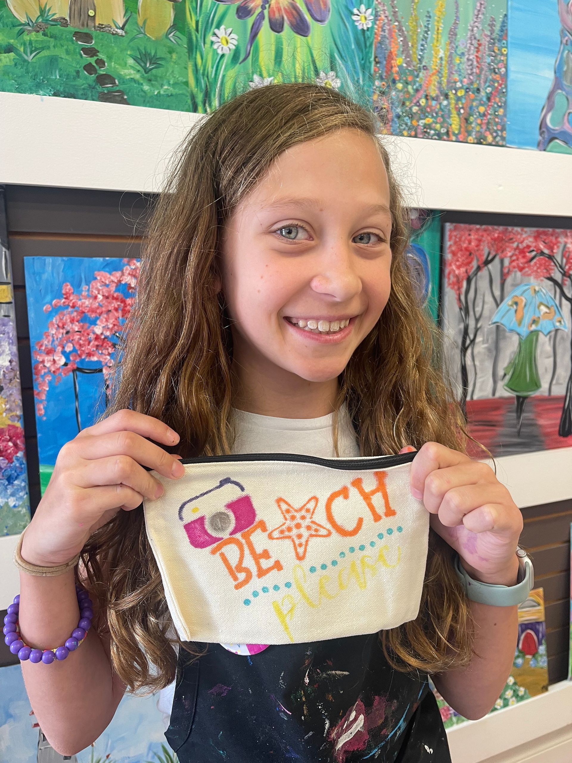 A young girl is holding a purse with the word beach on it.