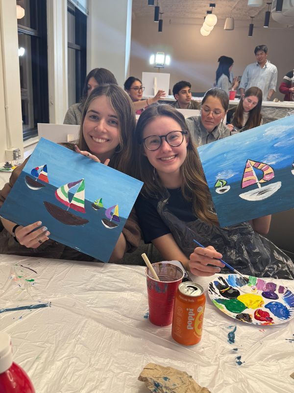 Group at paint and sip party posing with their paintings