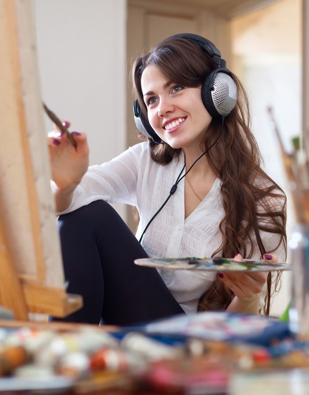 woman painting on canvas with headphones on