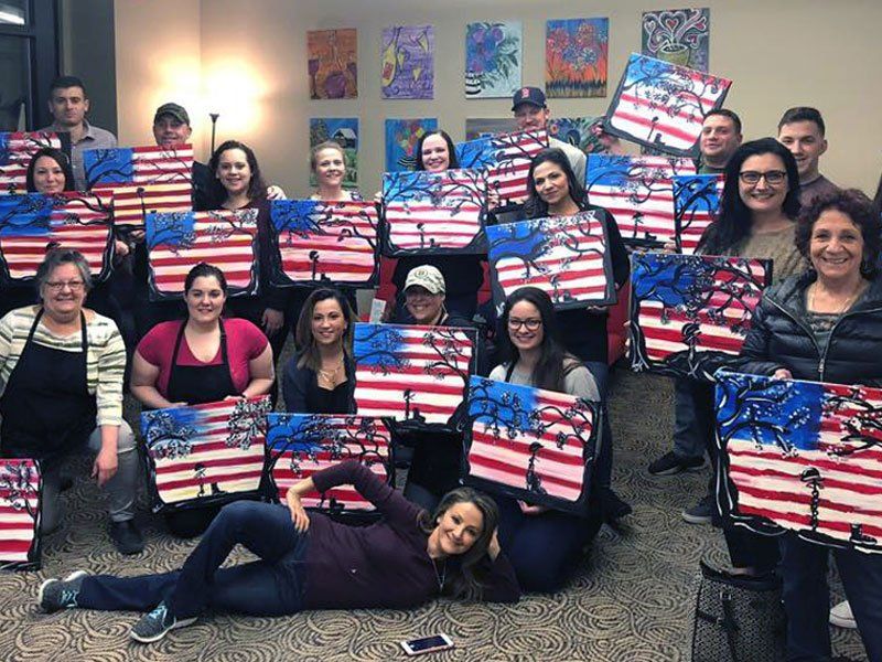 group painting class posing with American flag canvases