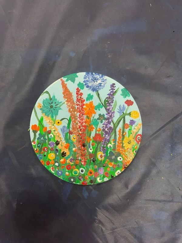 A painting of flowers on a circle on a table.