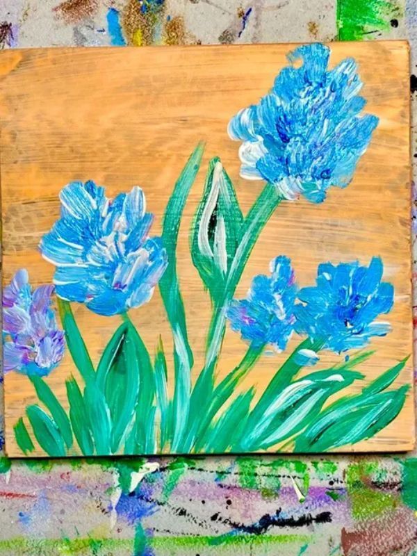 A painting of blue flowers on a wooden board