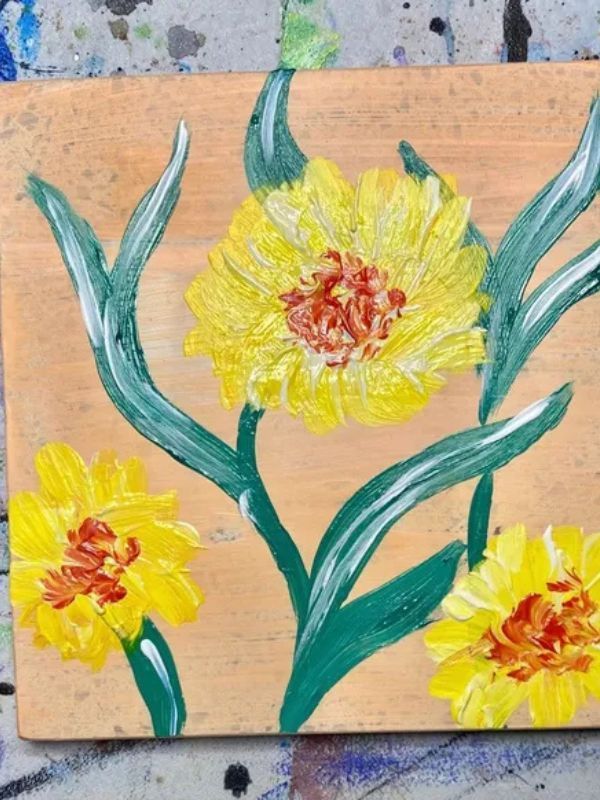 A painting of yellow flowers on a wooden board