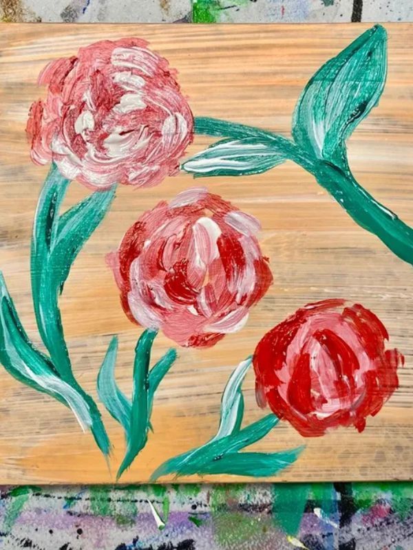 A painting of three roses on a wooden board
