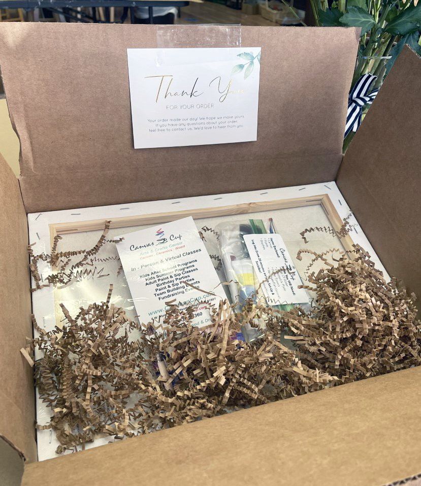 A cardboard box filled with shredded paper and a thank you note