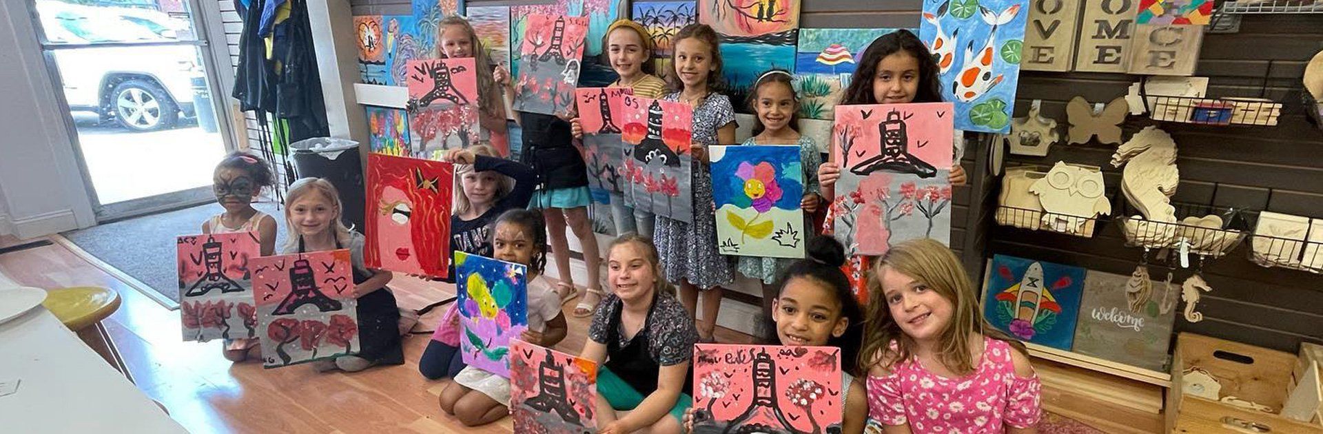A group of young girls are posing for a picture with their paintings.