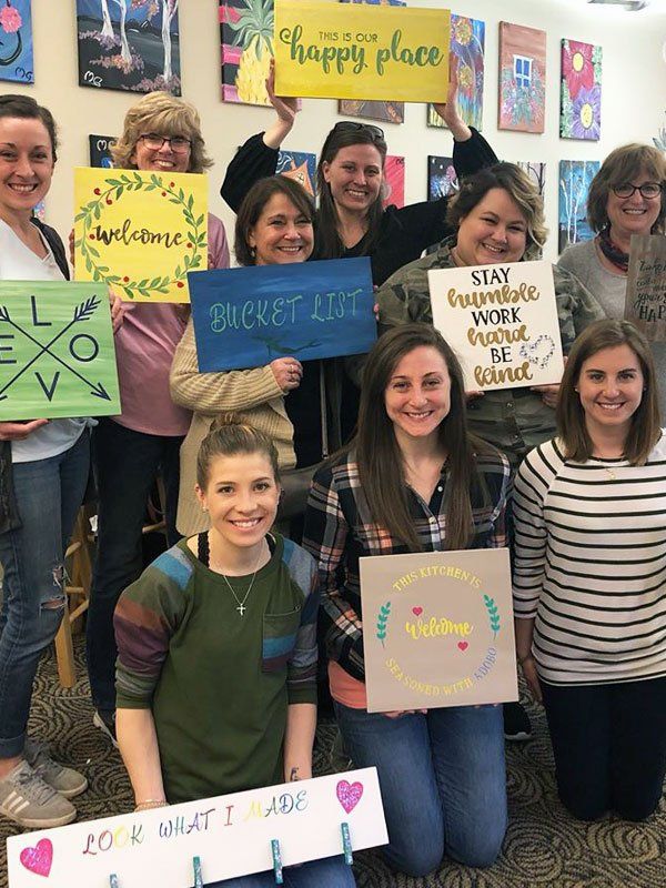 group posing with wooden signs after class