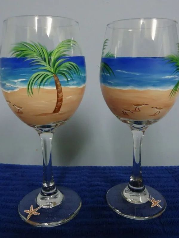 Two wine glasses with a beach scene painted on them