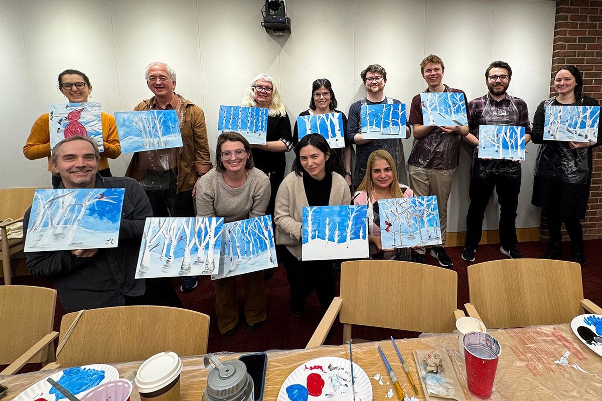 Group at paint and sip party posing with their paintings