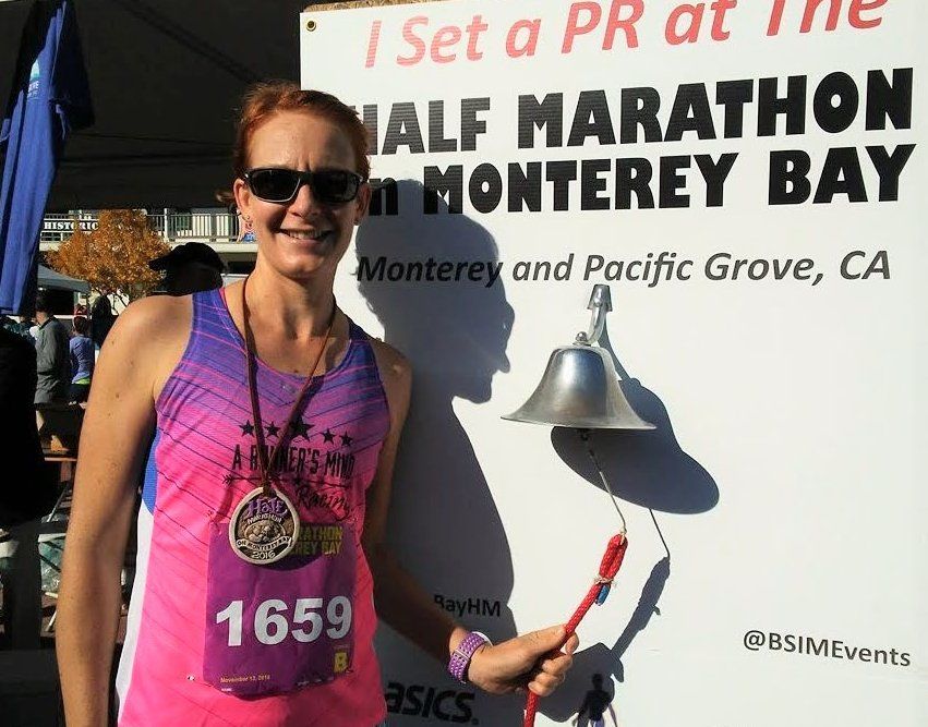 Woman runner celebrating PR and medal at the end of a half marathon race