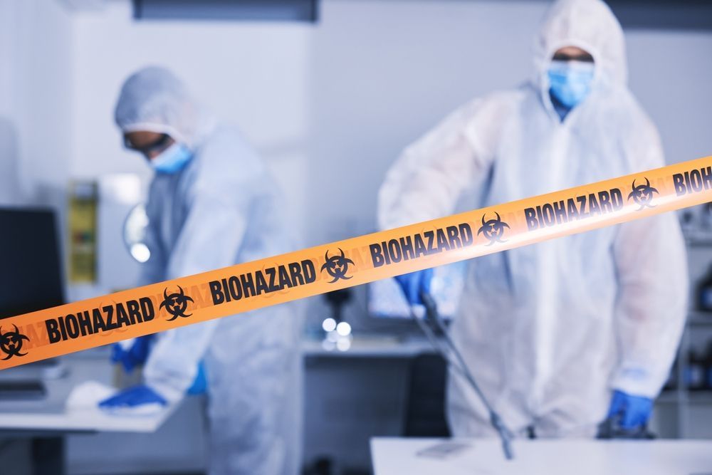 A man in a protective suit is standing next to a tape that says `` biohazard ''.