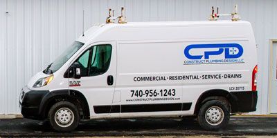 a white Construct Plumbing Design branded van is parked in front of a building