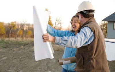 a man and a woman are looking at a remodeling blueprint on a construction site