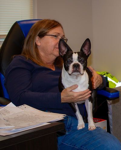 a woman is sitting in a chair holding a black and white dog