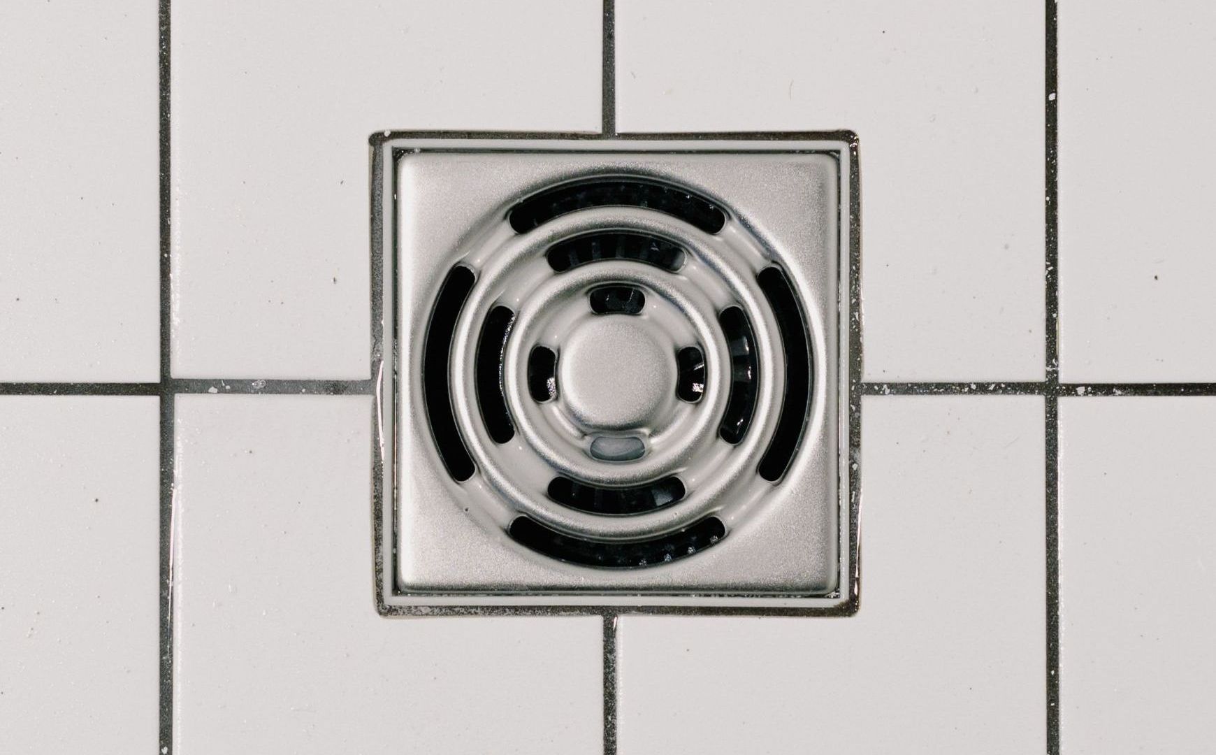 a drain on a tiled floor has a circular design on it