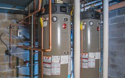 two water heaters are sitting next to each other in a basement