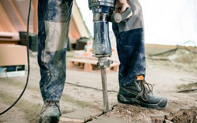 a man is using a jackhammer to break a hole in the ground for a well system